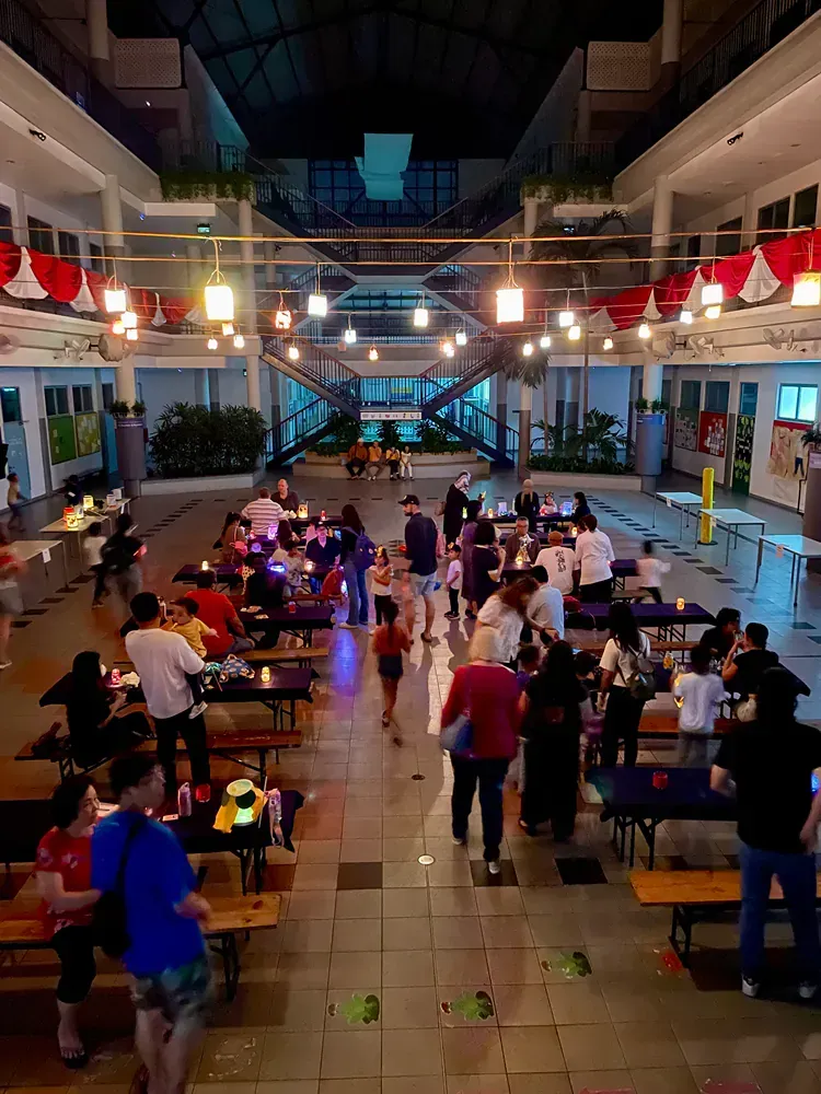 A group of people are standing around tables in a large room.