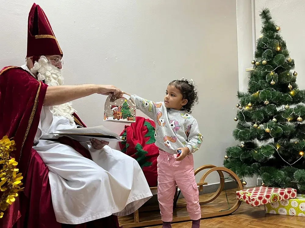 A little girl is standing next to a man dressed as santa claus.