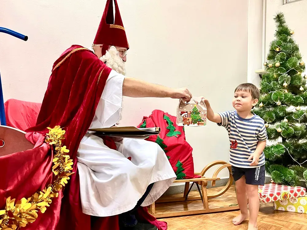 A little boy is standing next to a man dressed as santa claus.