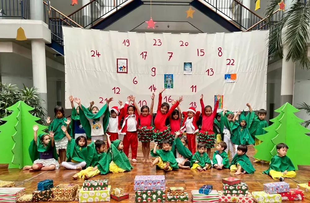 A group of children are posing for a picture in front of an advent calendar.