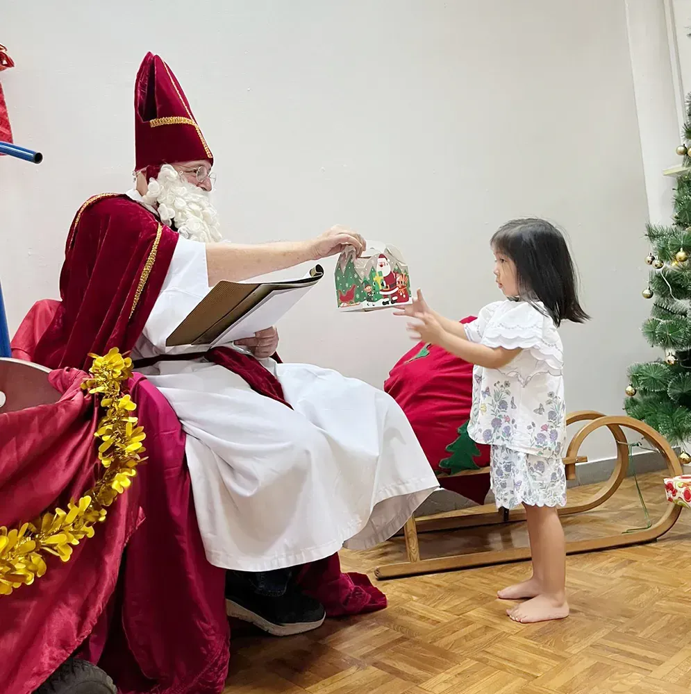A little girl is standing next to a man dressed as santa claus.
