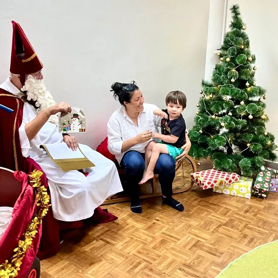 A man in a santa hat is sitting next to a woman holding a child in front of a christmas tree.