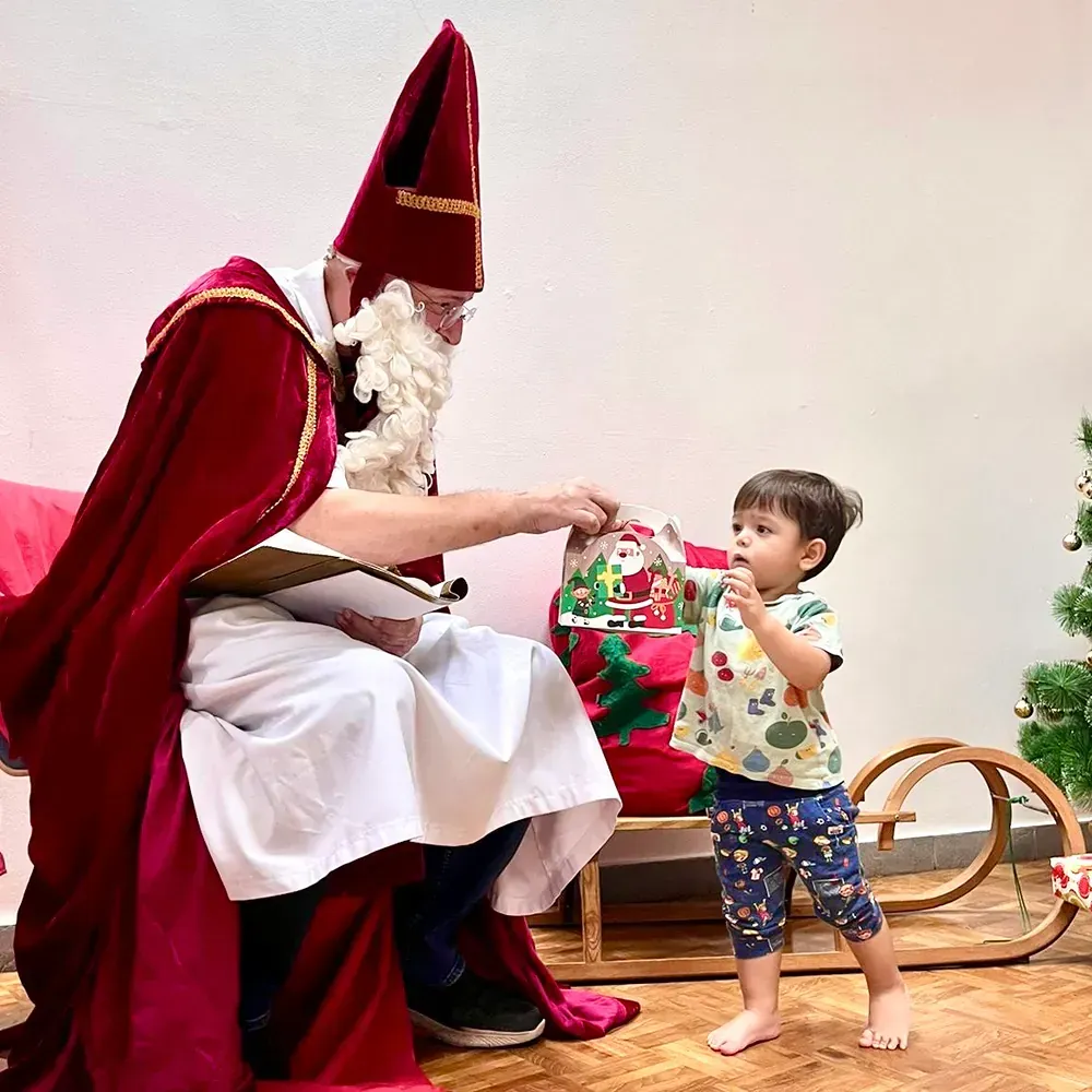 A little boy is standing next to a man dressed as santa claus.