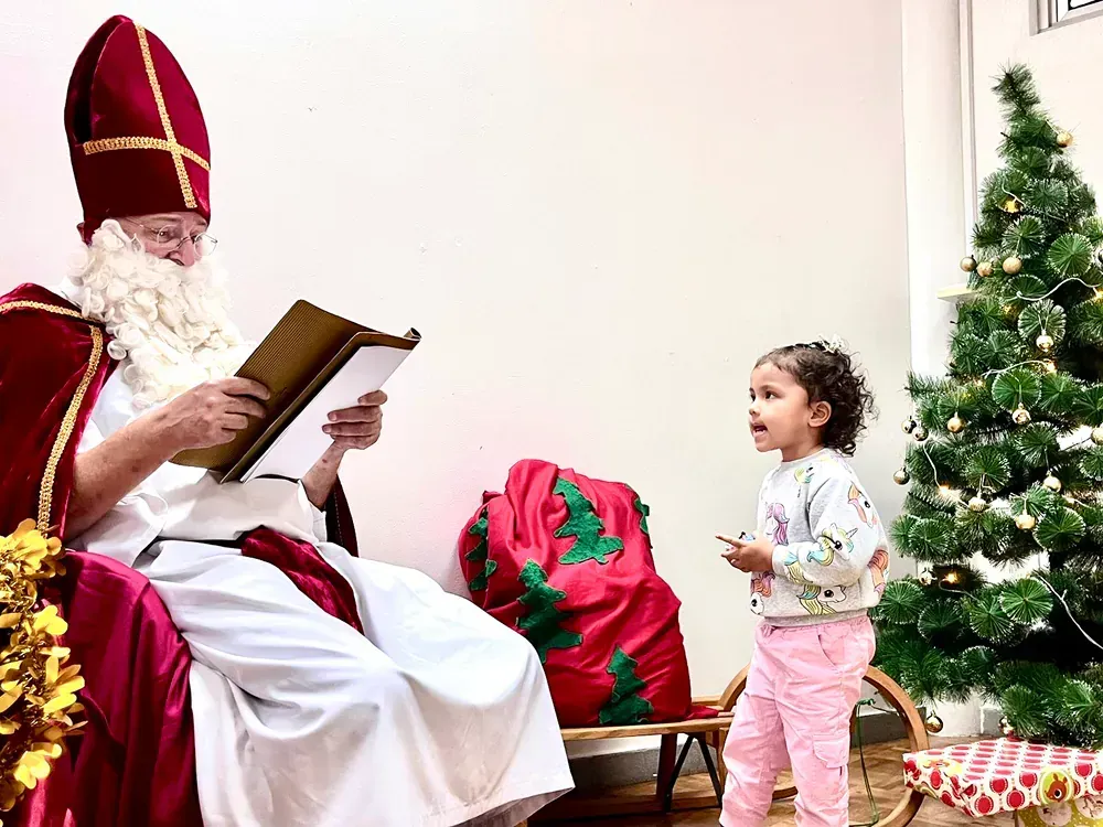 A little girl is standing next to a man dressed as santa claus.
