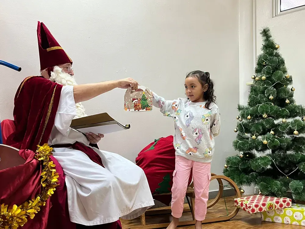 A little girl is giving a gift to santa claus.