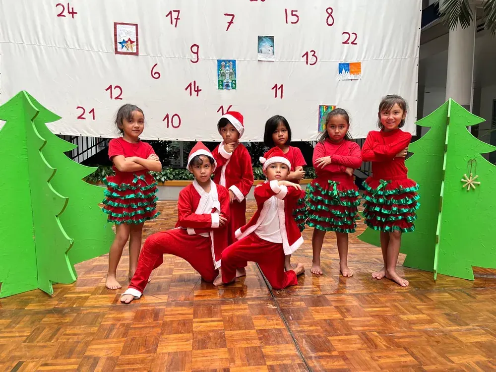 A group of children are posing for a picture in front of a christmas calendar.