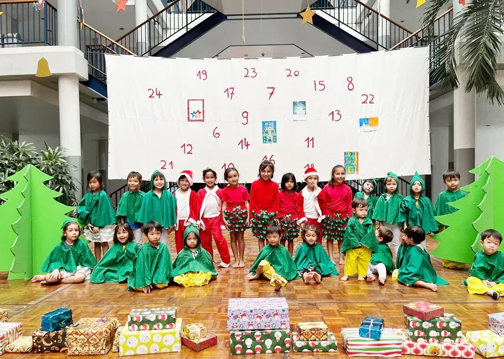 A group of children are posing for a picture in front of an advent calendar.