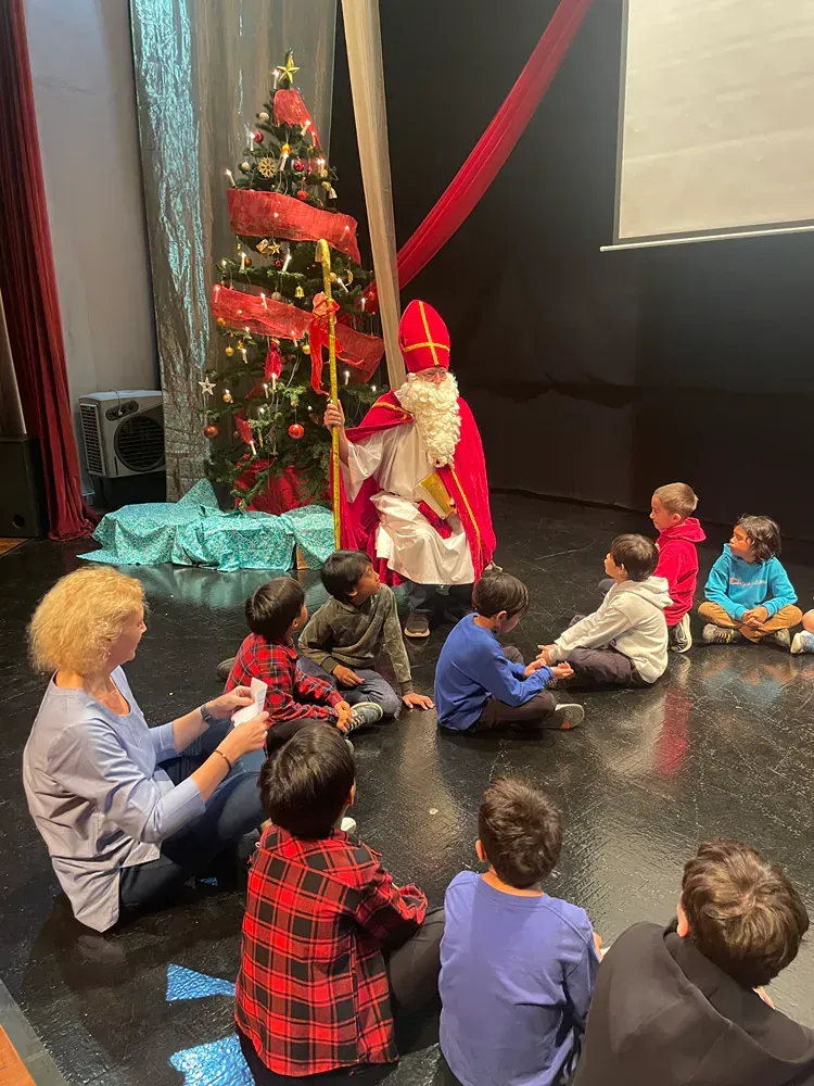 A group of children are sitting on the floor in front of a christmas tree.