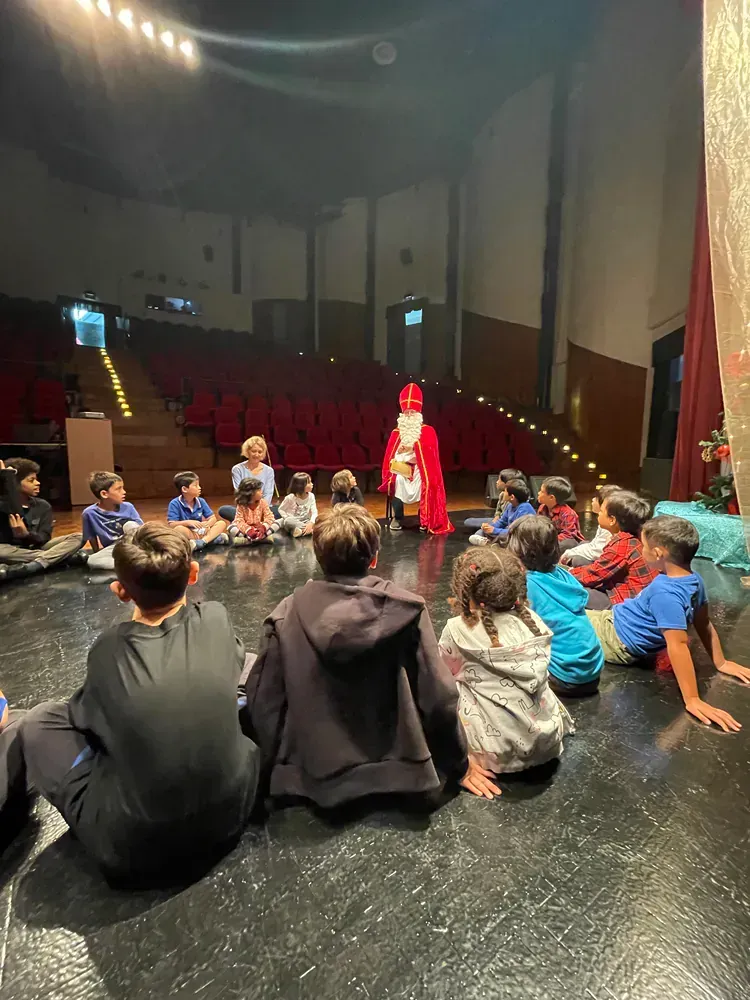A group of children are sitting on the floor in a theater watching a performance.