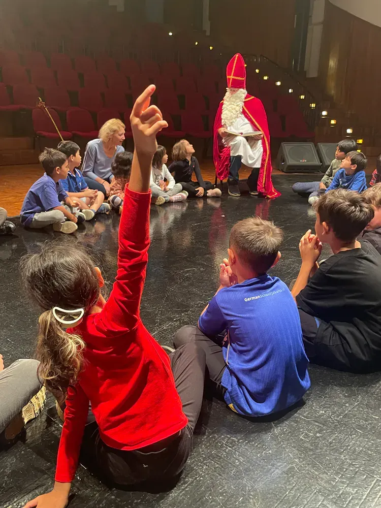 A group of children are sitting on the floor in a circle with santa claus.