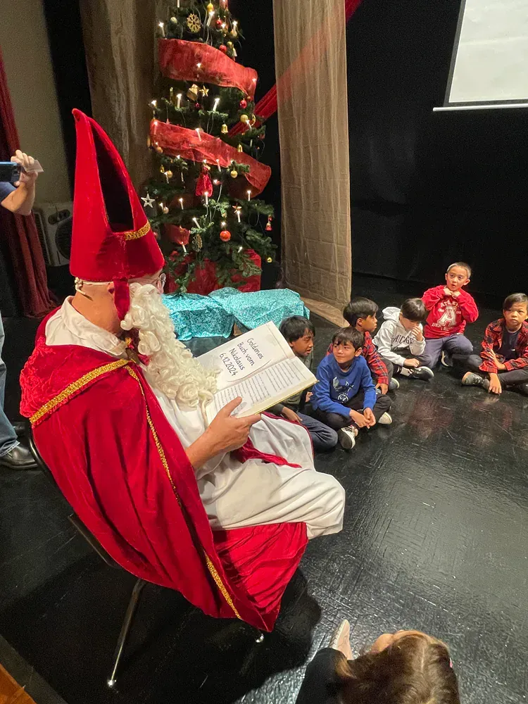 A man dressed as santa claus is reading a book to a group of children.