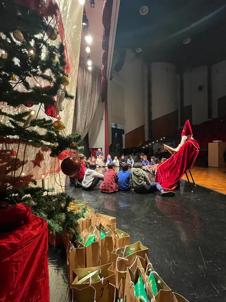 A group of people are sitting on the floor in front of a christmas tree.