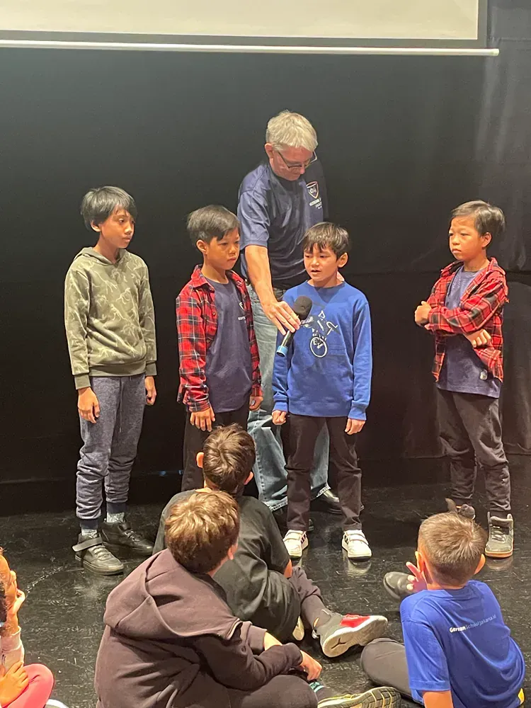 A man is standing next to a group of young boys on a stage.
