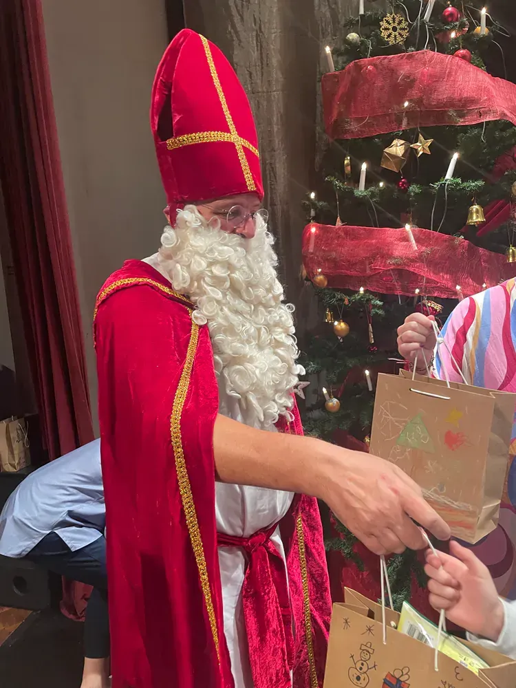 A man dressed as santa claus is standing in front of a christmas tree.
