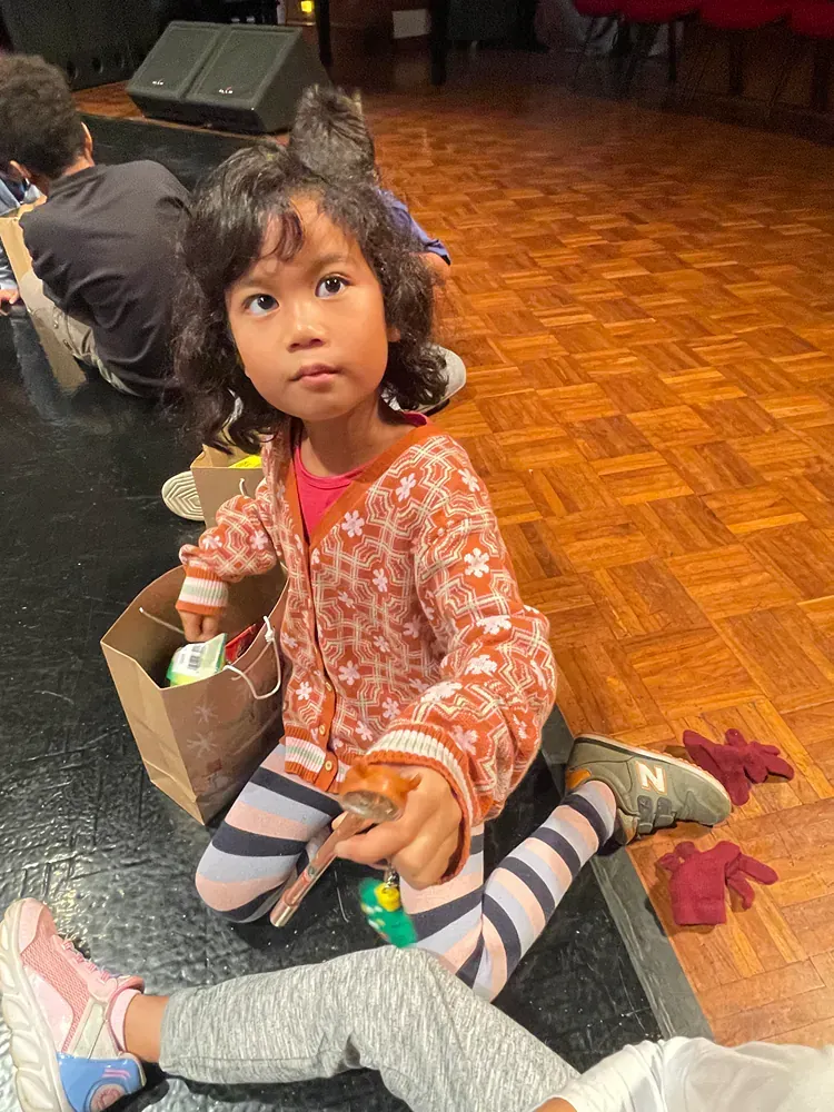 A little girl is sitting on the floor holding a toy.