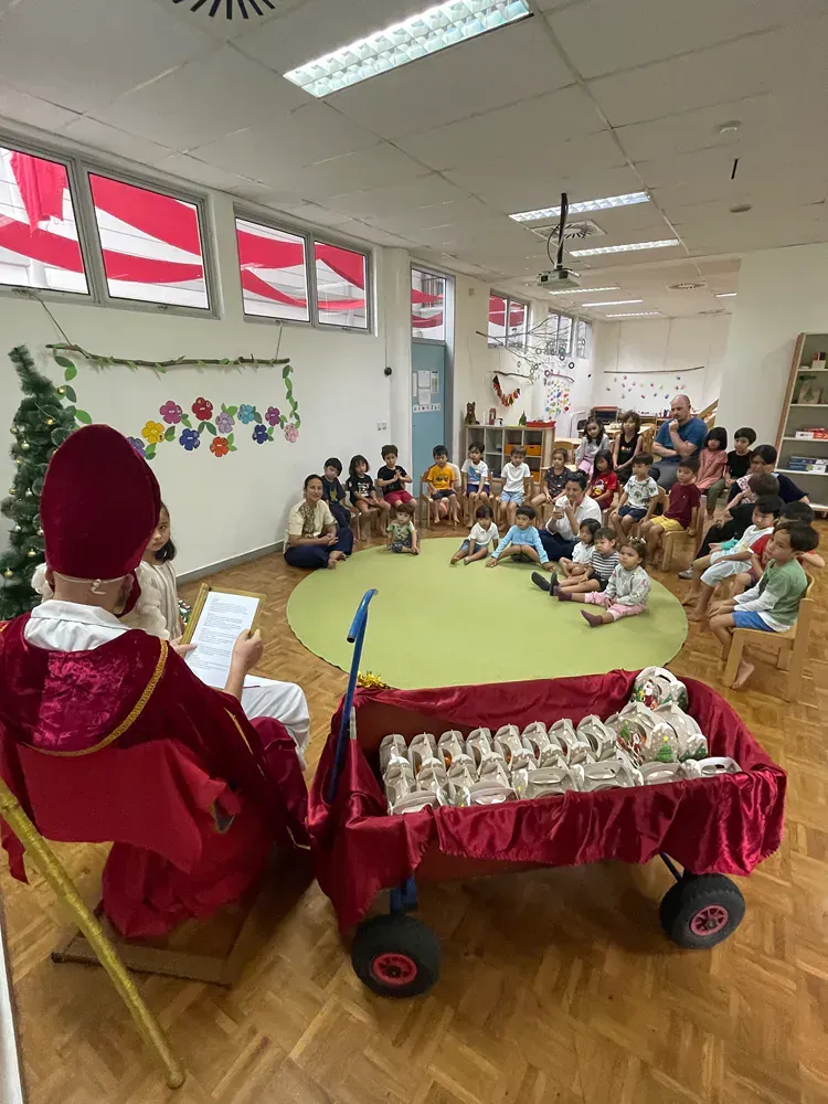 A man is reading a book to a group of children in a classroom.