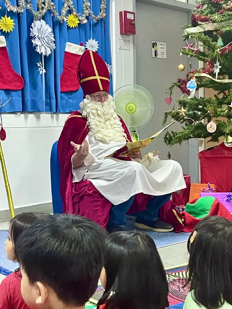 A man dressed as santa claus is reading a book to a group of children.