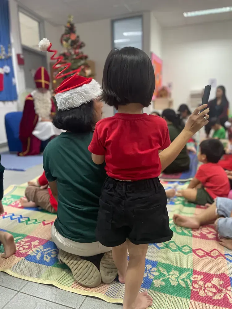 A woman and a little girl are sitting on the floor in front of a christmas tree.