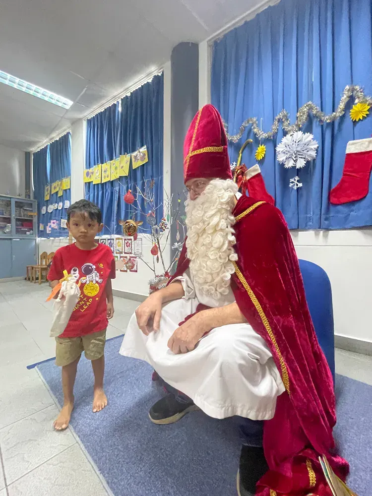 A little boy is standing next to a man dressed as santa claus.