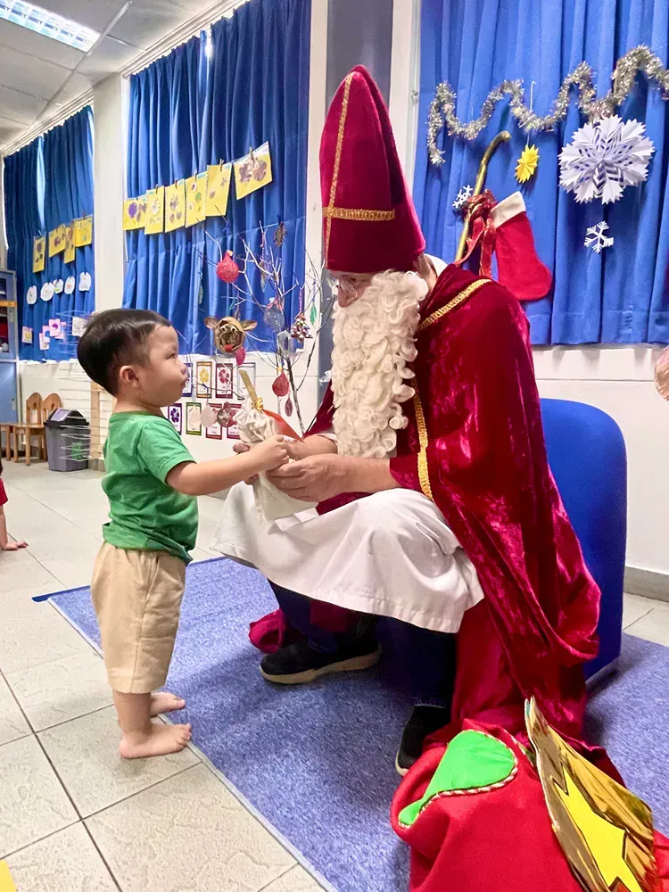 A little boy is standing next to a man dressed as santa claus.