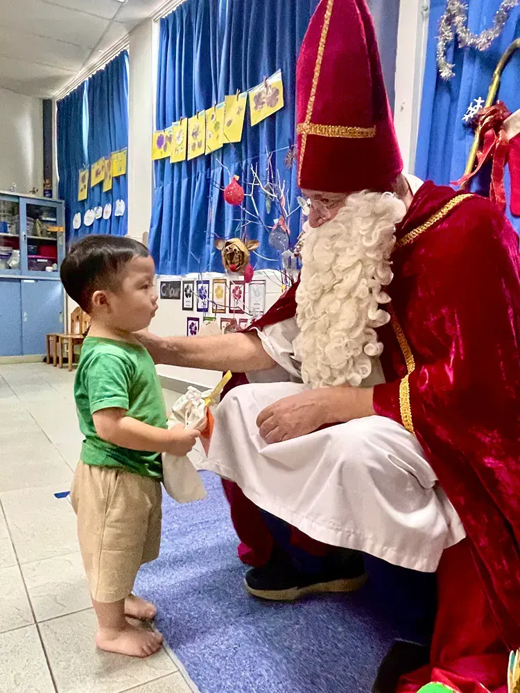 A little boy is standing next to a man dressed as santa claus.