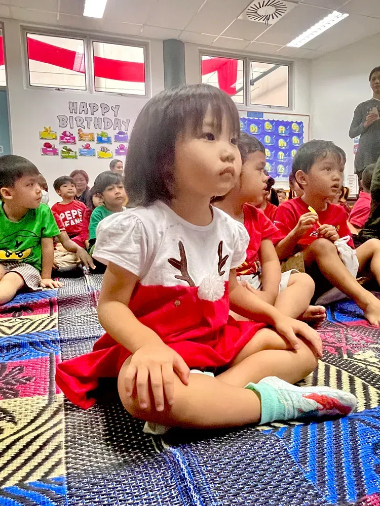 A group of children are sitting on the floor in a classroom.