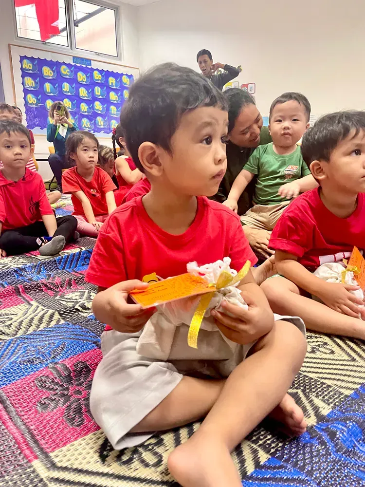A group of children are sitting on the floor in a classroom.