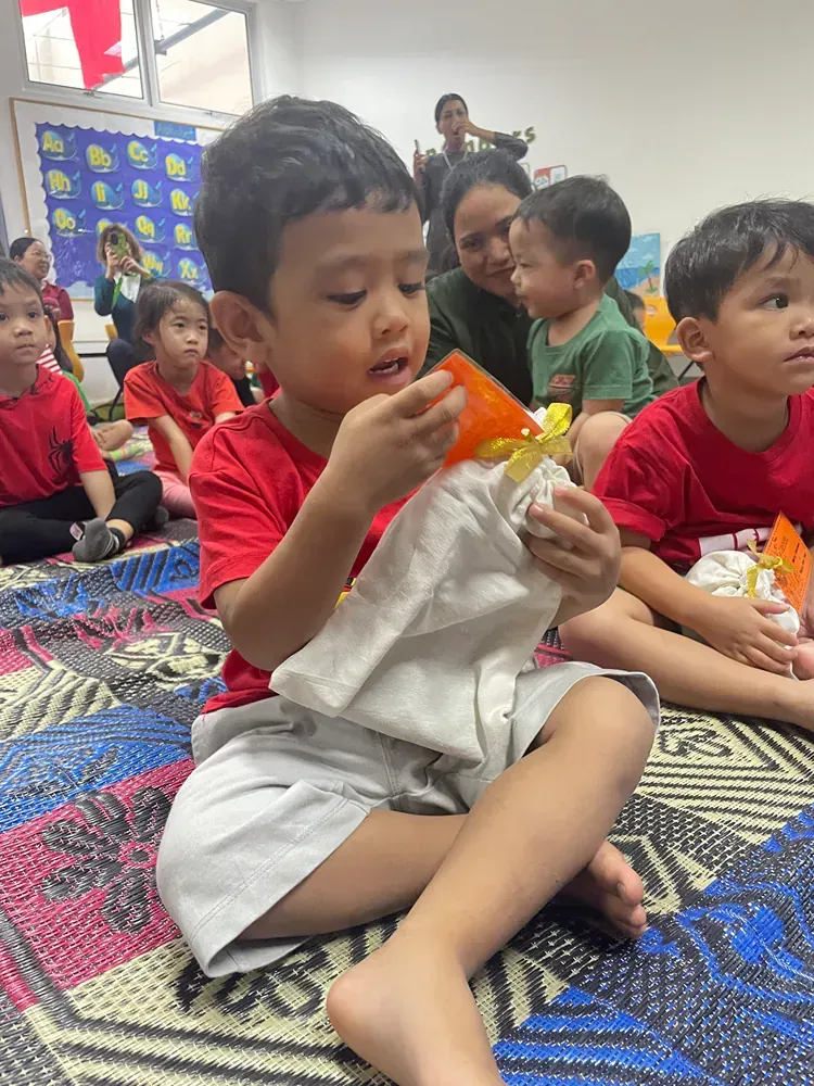 A group of children are sitting on the floor eating food.