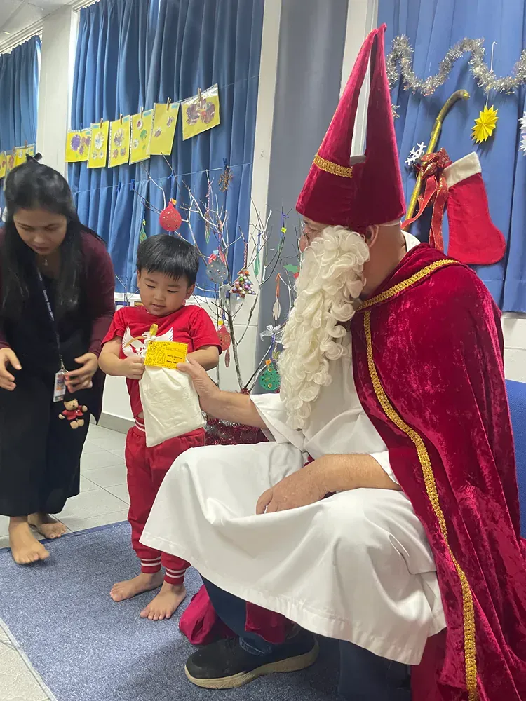 A man dressed as santa claus is sitting next to a little boy.
