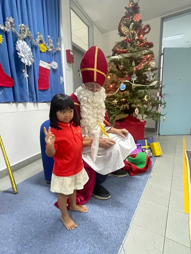 A little girl is standing next to a man dressed as santa claus.