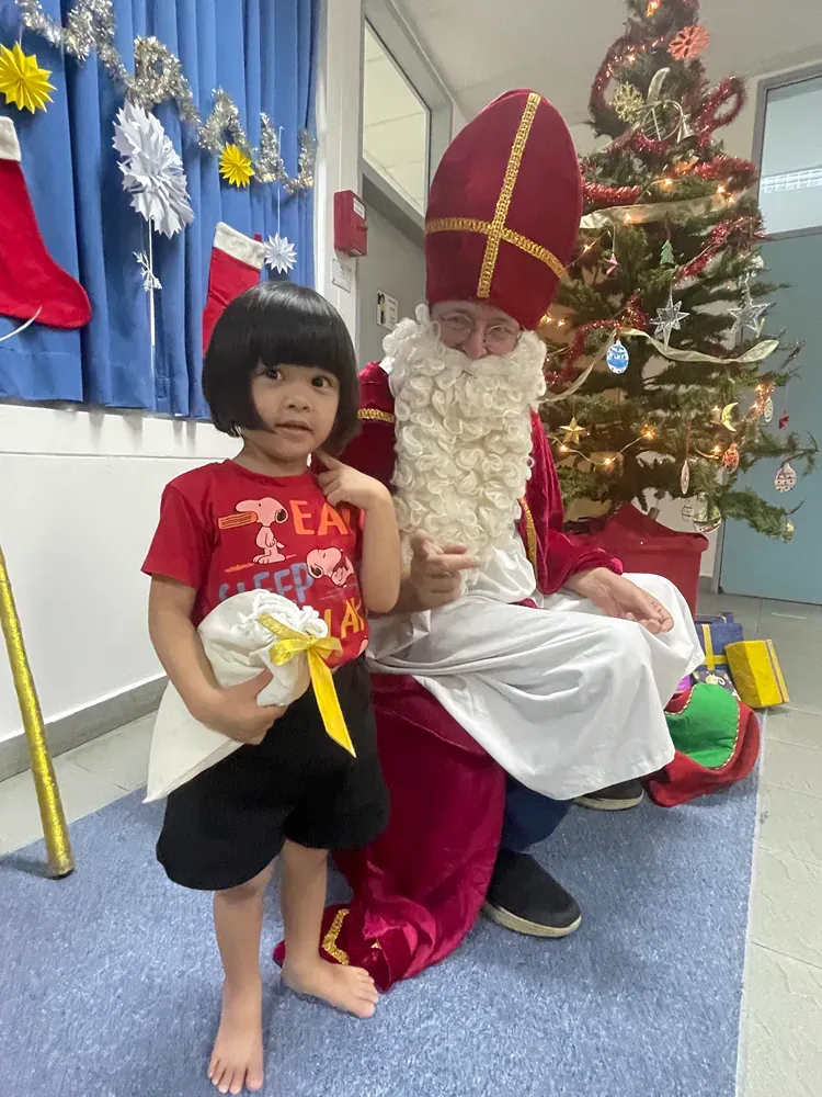A little girl is sitting next to a man dressed as santa claus.