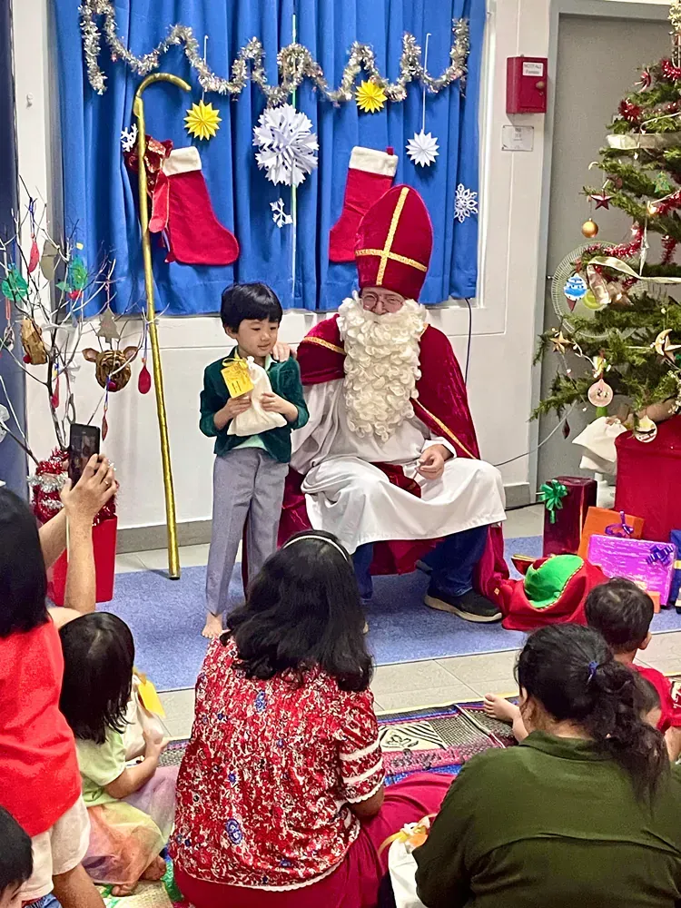 A group of children are sitting around a man dressed as santa claus.