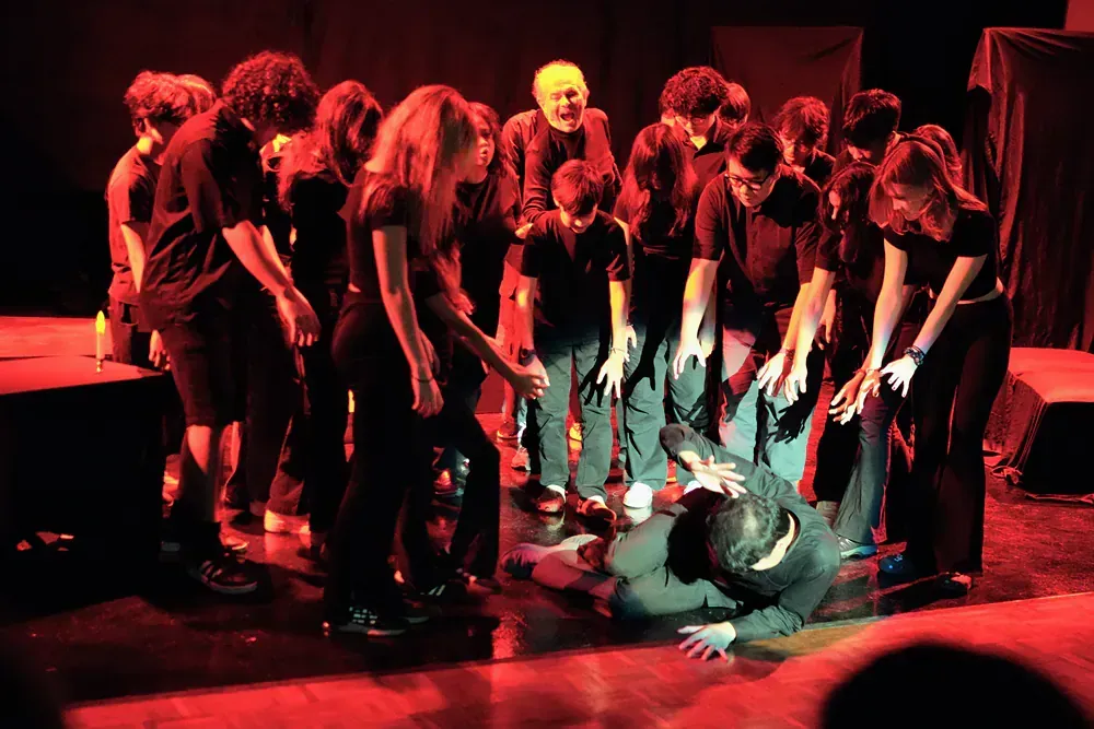 A group of people are standing around a man laying on the floor.