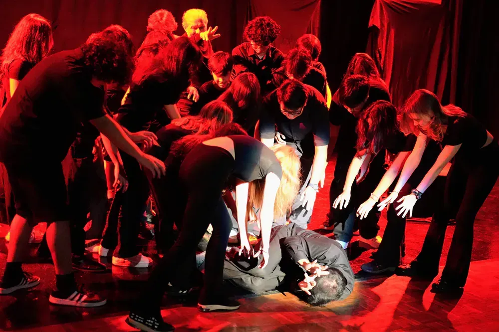 A group of people are standing around a man laying on the floor.