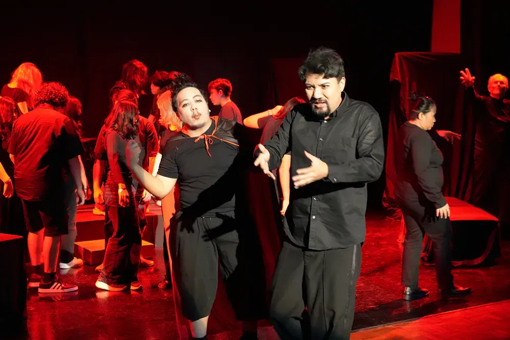 A group of people are standing on a stage in a dark room.