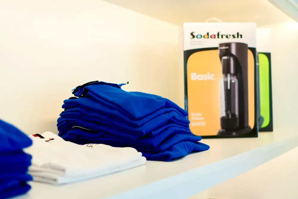 A stack of blue shirts next to a sodafresh box