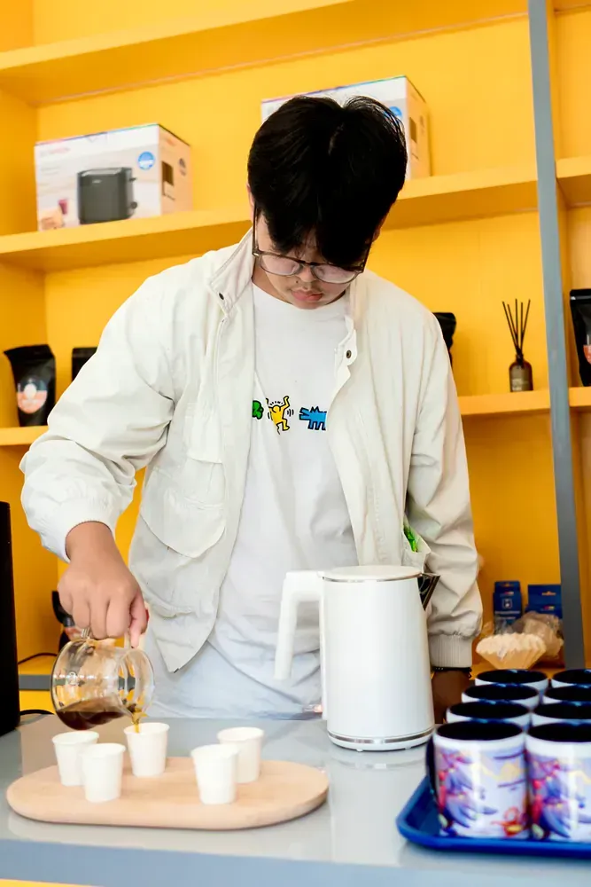 A man is pouring coffee into cups on a counter.