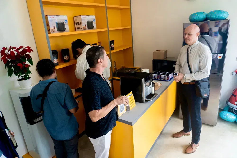 A group of people are standing around a counter in a room.