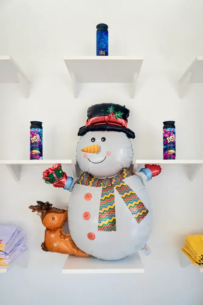 A large balloon in the shape of a snowman is sitting on a shelf.