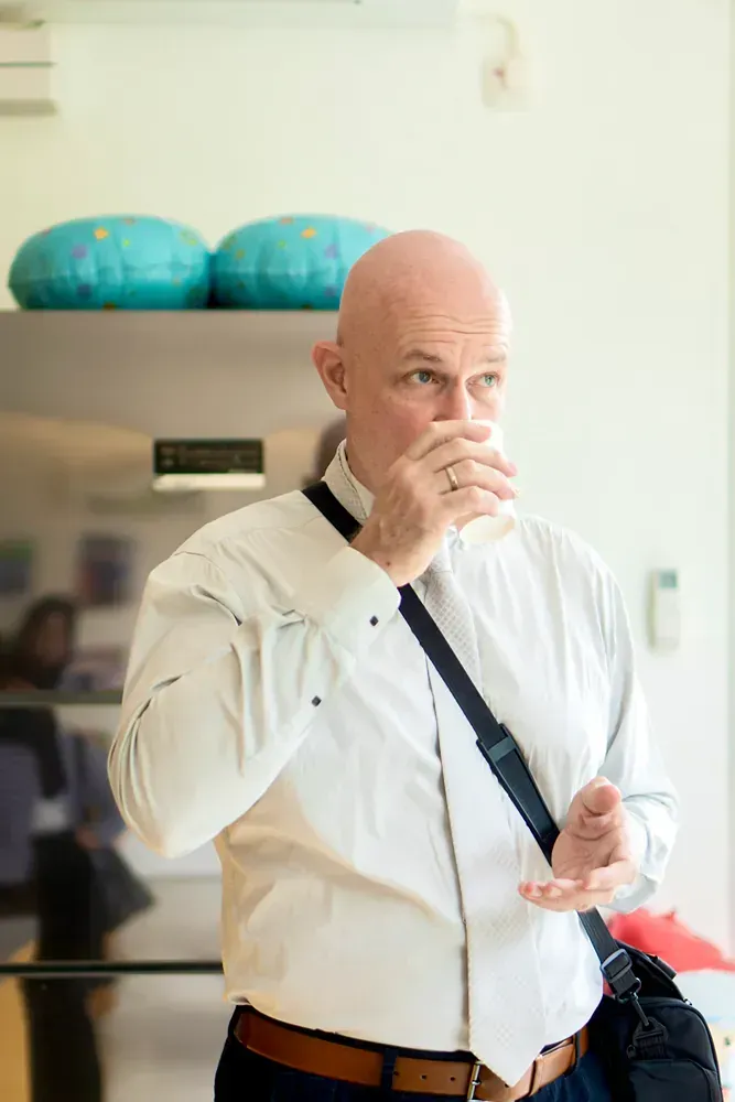 A man in a white shirt and tie is drinking a glass of water.