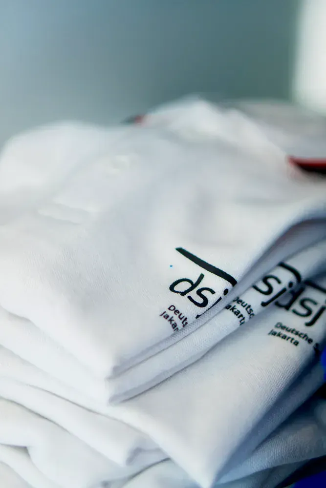 A stack of white shirts with the word dsi on them