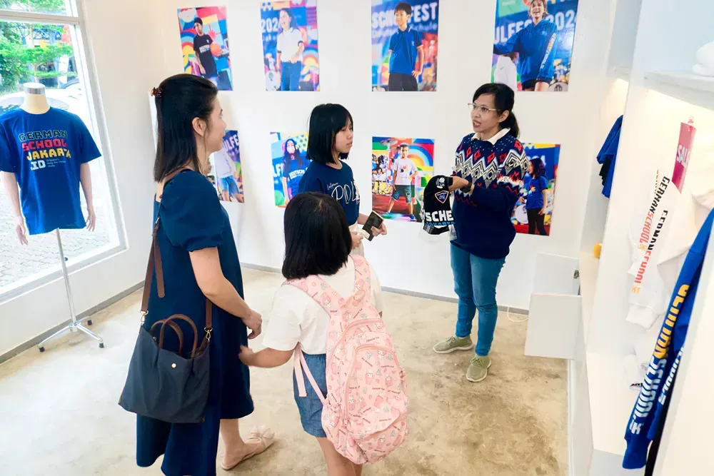 A group of people are standing in a room looking at shirts.