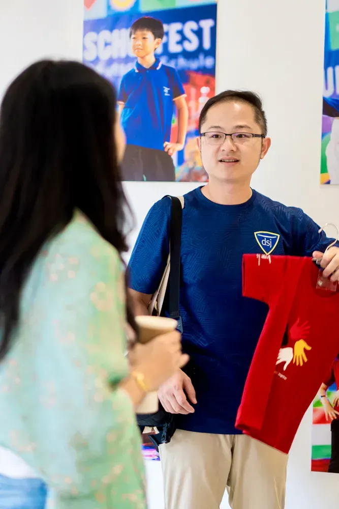 A man is holding a red t-shirt in front of a woman.