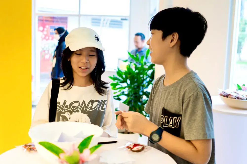 A boy and a girl are sitting at a table eating food.