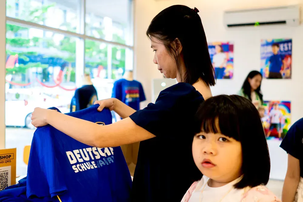 A woman is holding a blue t-shirt next to a little girl.