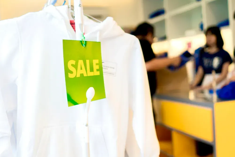 A white shirt is hanging on a hanger with a green sale tag attached to it.