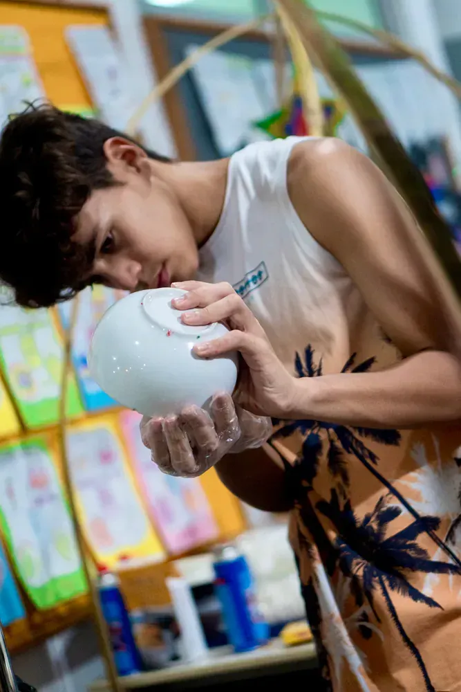 A young man is holding a white ball in his hands.