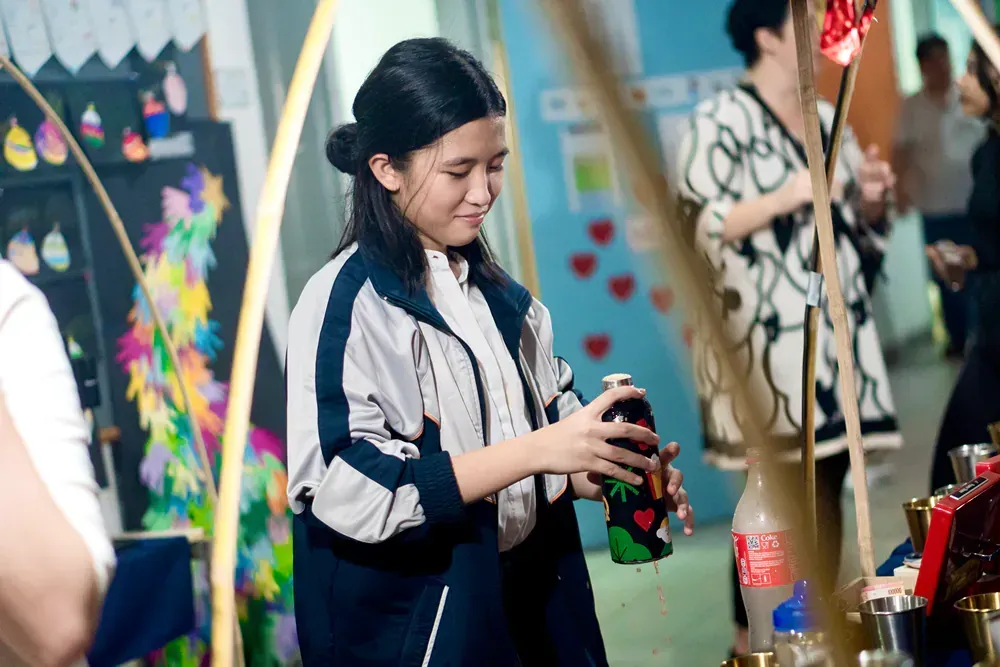 A young girl is holding a bottle of coca cola in her hands.