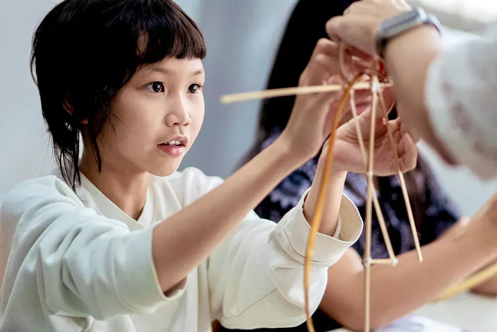 A young girl is playing with sticks in a classroom.