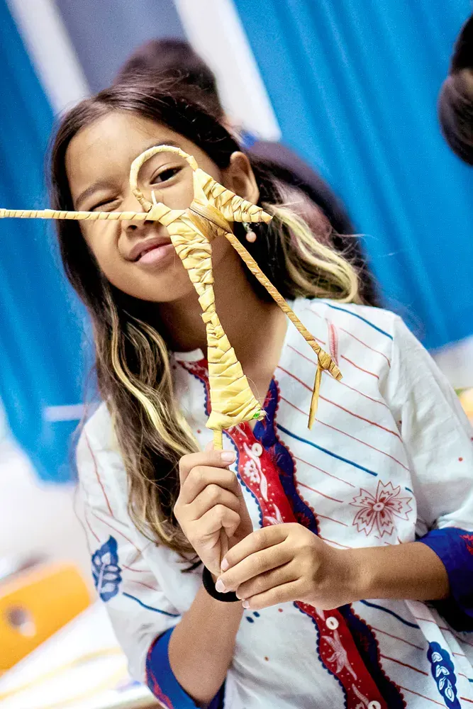 A young girl is holding a piece of yarn in front of her face.